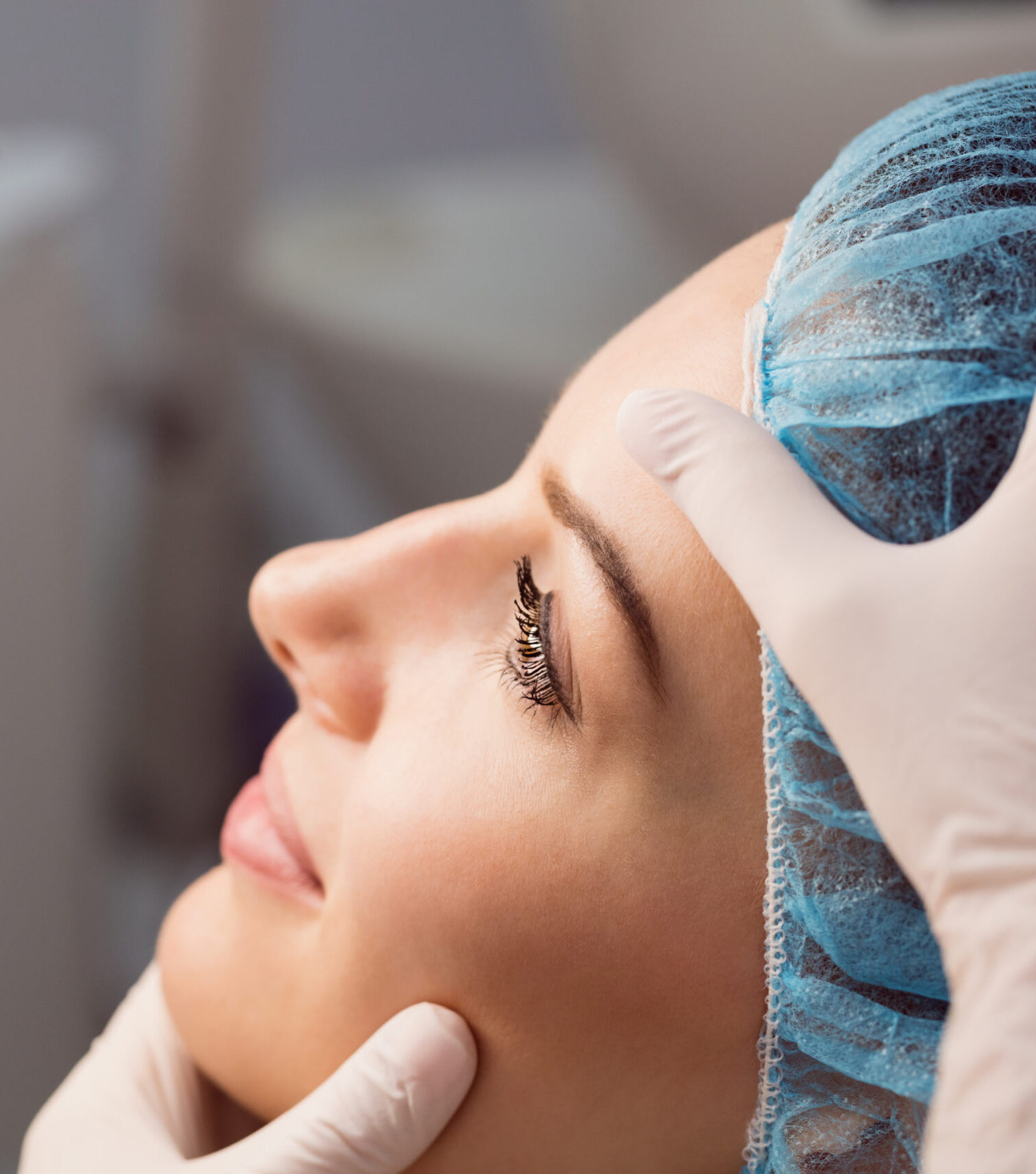 Hands of doctor examining womans face for cosmetic treatment at clinic